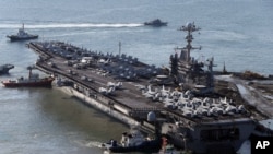 USS George Washington is escorted into a navy port in Busan, South Korea, Oct. 4, 2013.