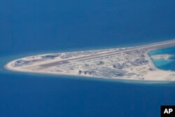 FILE - Chinese structures and an airstrip on the man-made Subi Reef at the Spratly group of islands in the South China Sea are seen from a Philippine Air Force C-130 transport plane of the Philippine Air Force, April 21, 2017.