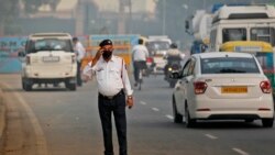 In this Nov. 4, 2019, file photo, a traffic officer wears a pollution mask and clears the irritants from his eyes in New Delhi, India. (AP Photo/Manish Swarup, File)