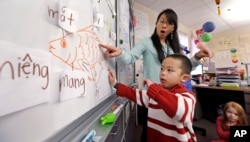 In this photo taken Feb. 14, 2014, kindergarten teacher Thao Tran helps student Brian Ho learn fish-related words in Vietnamese in a dual immersion language class at White Center Heights Elementary School in Seattle, Washington (AP Photo/Elaine Thompson)