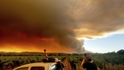 FILE - In this Aug. 20, 2020, file photo, Thomas Henney, left, and Charles Chavira watch a plume spread over Healdsburg, California.