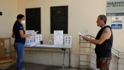 Un hombre conversa con una empleada de la biblioteca de Miami Beach después de recibir un formulario de desempleo al tiempo que la crisis del COVID-19 avanza en el país.