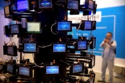 FILE - In this Sept. 12, 2017, file photo, an attendee looks at a digital representation of network connectivity at a vendor's display booth at the China Internet Security Conference in Beijing.
