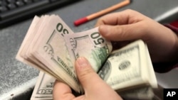 Клиент пересчитывает деньги у банке (архивное фото).