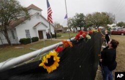 Rachel Vasquez places flowers in a fence for the victims of the shooting outside of the Sutherland Springs Baptist Church following a service held at a temporary site, Nov. 12, 2017, in Sutherland Springs, Texas.