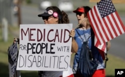 Protesters stand outside a radio station where Sen. Ted Cruz, R-Texas, stopped for an interview, July 6, 2017, in San Antonio. Cruz was to hold a town hall in Austin, Texas, on Thursday as a Republican bill to repeal and replace former President Barack Obama's health care law hangs in the balance.