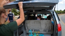 Laura Brooks' daughter Scarlett looks back as free groceries are loaded in their minivan at the monthly Weymouth Market in South Weymouth, Massachusetts, U.S., August 5, 2020. REUTERS/Brian Snyder