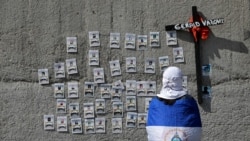 Un manifestante con la bandera nacional mira fotos de manifestantes que murieron durante las protestas contra el gobierno del presidente nicaragüense Daniel Ortega el año pasado, después de un servicio religioso. Managua, Nicaragua, el 2 de noviembre de 2