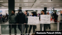 Des bénévoles tiennent des pancartes écrites en arabe "Avez-vous été détenu ?" à l'aéroport international de Washington DC, le 31 janvier 2017. (VOA/Nastasia Peteuil)