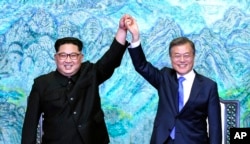 North Korean leader Kim Jong Un, left, and South Korean President Moon Jae-in raise their hands after signing a joint statement at the border village of Panmunjom in the Demilitarized Zone, South Korea, April 27, 2018.