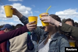FILE - Revelers hold up yellow plastic cups during party in New Jersey, Oct. 17, 2015.