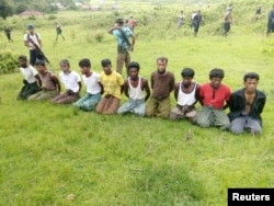 FILE - Ten Rohingya Muslim men with their hands bound kneel as members of the Myanmar security forces stand guard in Inn Din village, Sept. 2, 2017.