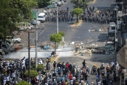 Army officers intervene during a protest against the military coup in Yangon, Myanmar, March 2, 2021. Picture taken from behind a window. REUTERS/Stringer