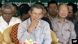 Cambodia's Prime Minister Hun Sen, center, smokes as he sits with Interior Minister Sar Kheng, left, and former Finance Minister Keat Chhun, right, during the inauguration of the China-funded construction of a bridge in Mouk Kampoul district, Kandal province, file photo.