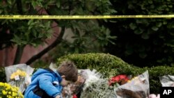 Dečak ostavlja cveće na mestu zločina ispred sinagoge