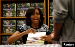 U.S. first lady Michelle Obama looks up as she signs a copy of her book "American Grown: The Story of the White House Kitchen Garden and Garden Across America" at the Politics & Prose bookstore in Washington May 7, 2013. REUTERS/Kevin Lamarque (UNITED