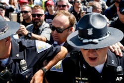 FILE - Alex Jones (C), an American conspiracy theorist and radio show host, is escorted out of a crowd of protesters after he said he was attacked in Public Square on July 19, 2016, in Cleveland, during the second day of the Republican convention.