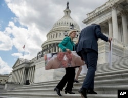Senate Minority Leader Sen. Chuck Schumer of N.Y., right, and Sen. Elizabeth Warren, D-Mass., carry photographs of their constituents who would be adversely affected by the proposed Republican Senate health care bill after speaking to reporters outside the Capitol in Washington, June 27, 2017.
