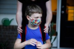 Rachel Adamus holds her son Paul, 7, in front of their house before the bus arrives for the first day of school on Monday, Aug. 3, 2020, in Dallas, Georgia, USA.