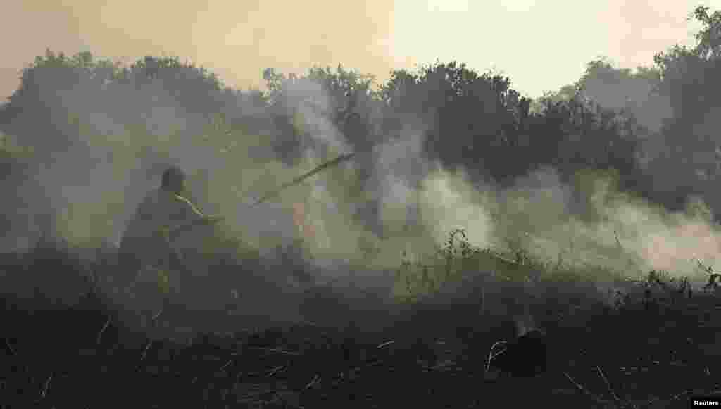 A resident tries to extinguish a fire burning on peatland in Pekanbaru of Riau province June 24, 2013.