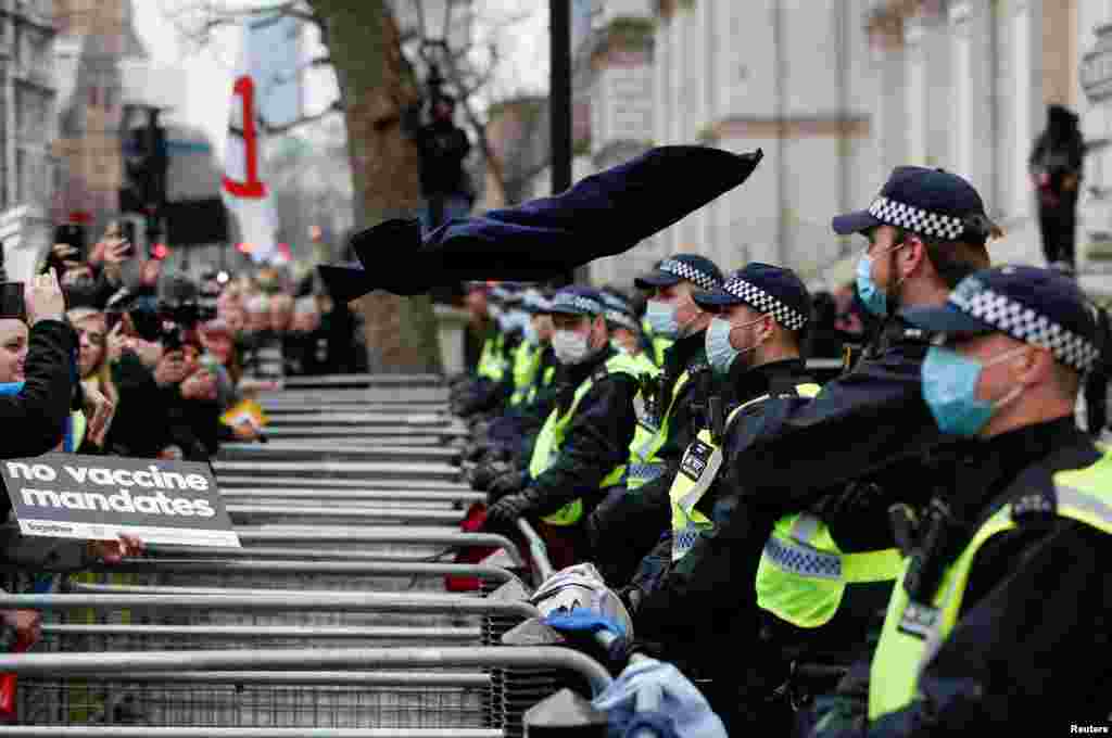 Police officers stand as NHS staff and others protesting against the COVID-19 vaccine rules throw NHS uniforms at the entrance to Downing Street in London.