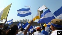 (ARCHIVO) Los manifestantes ondean banderas de Nicaragua y del Vaticano durante una marcha por "Paz y Justicia" convocada por la Iglesia Católica, en Managua, Nicaragua, el sábado 28 de abril de 2018.