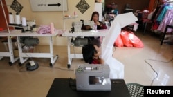 FILE - Nur Afia Qistina Zamzuri, a 9-year-old girl sews personal protective equipment (PPE) for free to medical workers working in local hospitals at her home with her mother Hasnah Hud, in Kuala Pilah, Malaysia, May 5, 2020.