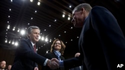 Senate Intelligence Committee Vice Chairman Mark Warner, D-Va., shake hands with FBI Director Christopher Wray as CIA Director Gina Haspel looks on before the Senate Intelligence Committee hearing on Capitol Hill in Washington, Jan. 29, 2019. 