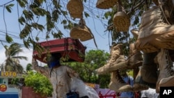 Una persona con un casco de motocicleta carga con unas maletas junto a un puesto de venta de botas militares cerca del aeropuerto de Puerto Príncipe, el 13 de mayo de 2024.
