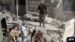 Војниците на либанската армија стојат настрана додека луѓето расчистуваат остатоци и урнатини на самото место каде Израел изврши воздушен напад врз селото Аито во северен Либан на 15 октомври 2024 година, Аито, Либан.