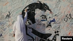 A man writes on a painting depicting Qatar’s Emir Sheikh Tamim bin Hamad Al-Thani in Doha, Qatar, July 2, 2017. The artwork has attracted comments of support from residents amid a diplomatic crisis between Qatar and neighboring Arab countries.