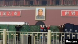 Police officers set up barriers in front of the giant portrait of the late Chinese Chairman Mao Zedong as they clean up after a car accident at Tiananmen Square in Beijing, Oct. 28, 2013. 