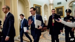 Treasury Secretary Steven Mnuchin, third from left, and White House Legislative Affairs Director Eric Ueland, left, walk to a meeting with Senate Minority Leader Sen. Chuck Schumer of N.Y. in his office on Capitol Hill, Monday, March 23, 2020.