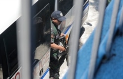 An armed police escort of opposition Senator Leila de Lima disembarks from their vehicle as she arrives to vote in the country's midterm elections Monday, May 13, 2019 in suburban Paranaque, southeast of Manila, Philippines.