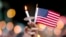 A mourner holds up an American flag and a candle during a vigil for a fatal shooting at an Orlando nightclub, June 12, 2016, in Atlanta.