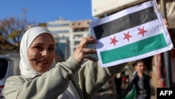 在敘利亞海濱城市拉塔基亞，一位女子亮出敘利亞反對派的旗幟。 (2024年12月10日)