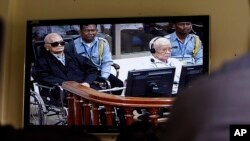 Khieu Samphan, second from right, former Khmer Rouge head of state, and Noun Chea, left, who was the Khmer Rouge's chief ideologist and No. 2 leader, is seen on a screen at the court's press center of the U.N.-backed war crimes tribunal in Phnom Penh, Cambodia.