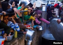 Palestinian children wait to receive food in Rafah, in the southern Gaza Strip during the Muslim holy fasting month of Ramadan, as the conflict between Israel and Hamas continues, March 13, 2024.