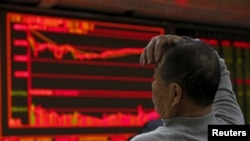 A man looks at an electronic board showing stock information at a brokerage house in Beijing, China, Jan. 4, 2016.