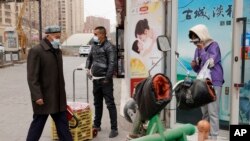 2021年3月18日，戴著口罩的居民走在中國西部新疆地區阿克甦的街道上。 (美聯社照片)