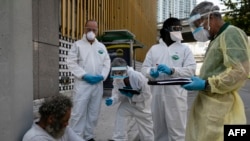 ဖလော်ရီဒါပြည်နယ် မိုင်ယာမီမြို့မှာ အိမ်ခြေရာမဲ့တဦးကို ကိုရိုနာဗိုင်းရပ်စ် စစ်ဆေးပေးဖို့ ပြင်ဆင်နေတဲ့ ကျန်းမာရေးဝန်ထမ်းများ။ (ဧပြီ ၁၆၊ ၂၀၂၀)