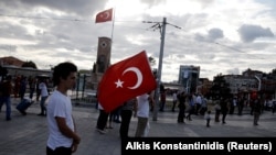 Un homme tient le drapeau turc sur la place Taksim à Istanbul, Turquie, le 20 juillet 2016. 