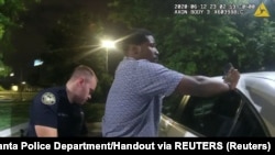 Askari wa zamani wa Idara ya polisi Atlanta Garrett Rolfe akichukua kipimo cha ulevi kutoka kwa Rayshard Brooks, katika eneo la mgahawa wa Wendy. 