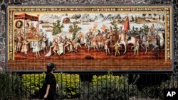 A woman walks past a mural commemorating the meeting of the Spanish conquistador Hernan Cortes and the Aztec Emperor Moctezuma in Mexico City, Tuesday, May 18, 2021. The capital of the Aztec empire, now known as Mexico City, fell after a prolonged siege 5