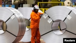 A worker inspects a steel coil on the factory floor of the ArcelorMittal Dofasco steel mill in Hamilton, Ontario, Canada, March 12, 2025. 