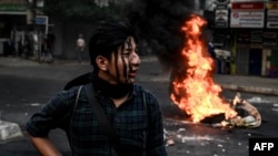 រូបឯកសារ៖ បាតុករ​ម្នាក់ ឈរ​នៅ​ជិត​ភ្នក់ភ្លើង​ដែល​ជា​របាំង​បណ្តោះ​អាសន្ន​ក្នុង​ពេល​តវ៉ា​ប្រឆាំង​នឹង​រដ្ឋប្រហារ​យោធា​នៅ​ទីក្រុង​រ៉ង់ហ្គូន កាលពី​ថ្ងៃទី៣០ ខែមីនា ឆ្នាំ២០២១។