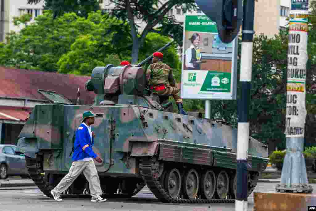 Un homme passe devant un char de l'armée zimbabwéenne où les soldats régulent le trafic routier, à Harare, au Zimbabwe, le 15 novembre 2017.