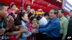 Prime Minister Hun Sen greets garment workers during a visit to a factory outside of Phnom Penh, Cambodia, Wednesday, Aug. 30, 2017. Hun Sen embarked on a country-wide trip to visit the nation's factory workers to hear their hopes and concerns in person. (AP Photo/Heng Sinith)