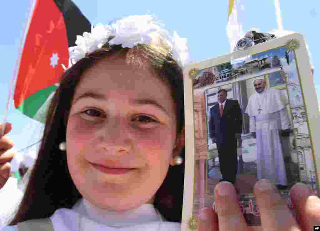 A young girl holds a photo of Pope Francis and Jordan's King Abdullah as people congregate at Amman's International Stadium to wait for the arrival of Pope Francis Amman, May 24, 2014.