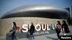 People wearing masks to protect against contracting the coronavirus disease (COVID-19) walk along a street in Seoul, South Korea March 25, 2020. REUTERS/Kim Hong-ji
